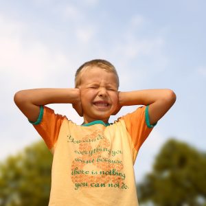 A young boy covering the ears by hands