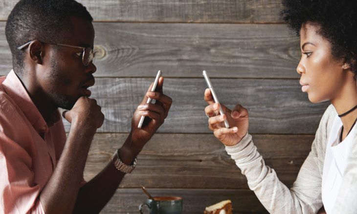People using mobile phones totally absorbed in online life, looking obsessed, not talking to each other, using wi-fi at cafeteria, facing one another